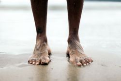 Tattooed feet on the sand on the beach.