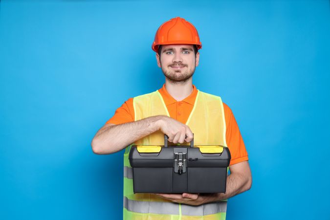 Engineer in helmet with suitcase of tools on blue background