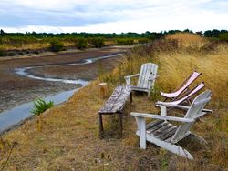 Long chairs and table overlooking marsh beside the path to Ars