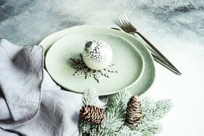 Light green table setting for Christmas dinner with snowball bauble ornament