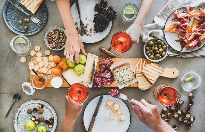 Charcuterie board with hands holding wine and reaching for food