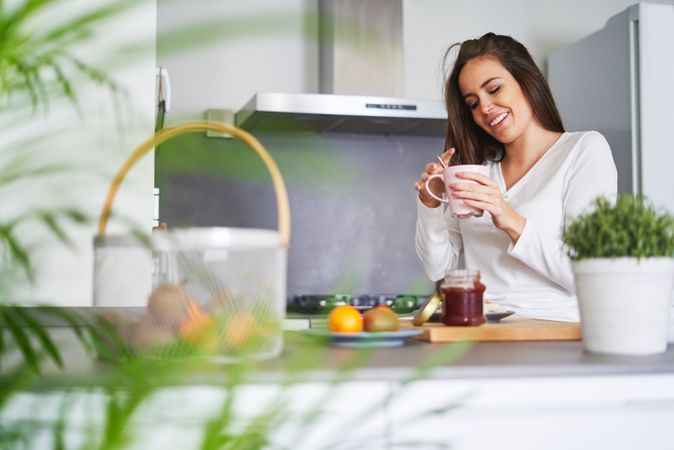 Woman drinking from cup in kitchen