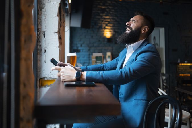 Man laughing with his head back in pub