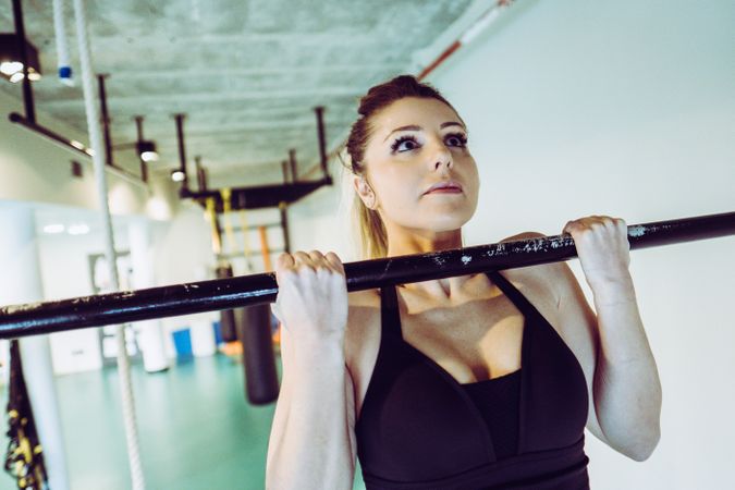 Young woman doing pull ups in gym