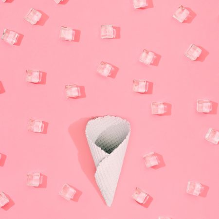 Cone with straw with ice cubes pattern on pastel pink background