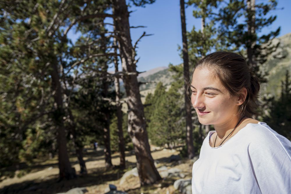 Young woman standing in the woods looking away from camera