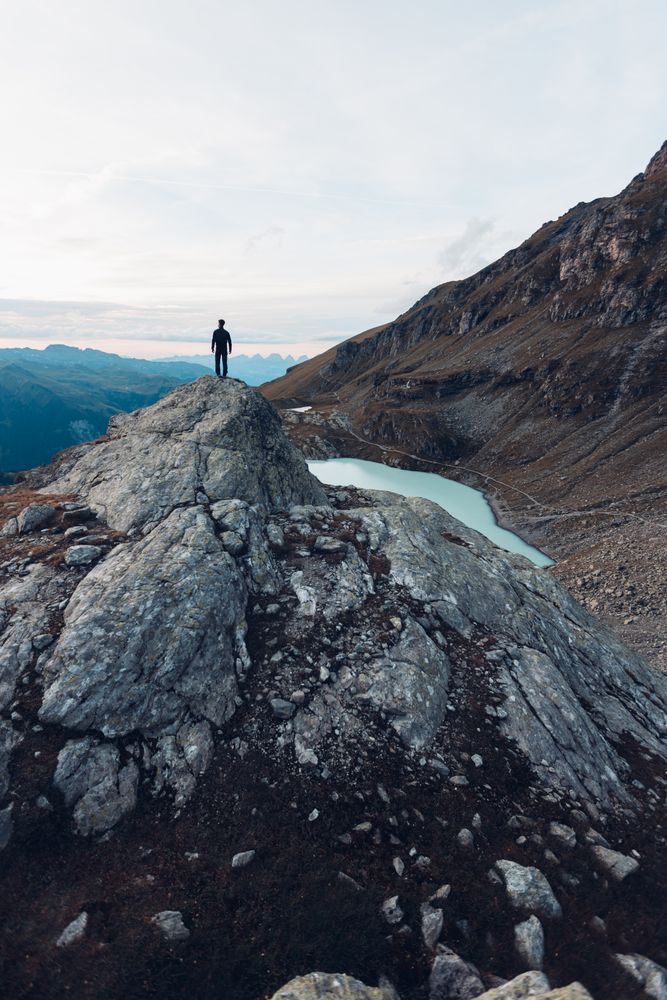 Man standing on waterside of frozen lake in the mountain