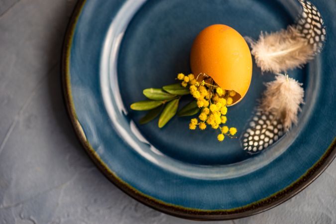 Close up of Easter table setting with egg and feather on blue plate