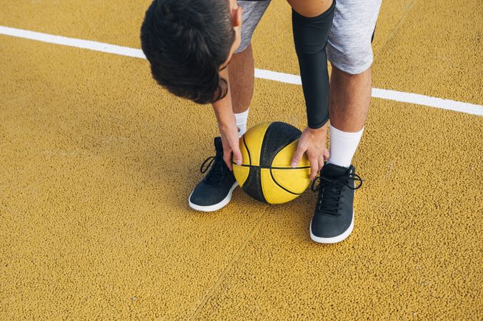legs of crop Young man and ball playing on basketball court outdoor.