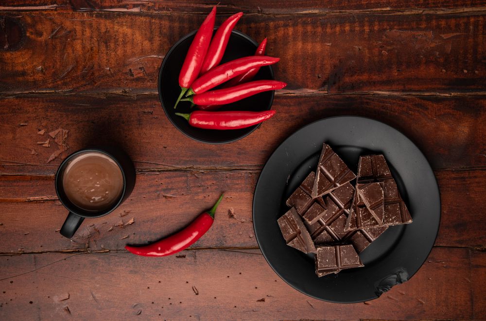 Hot beverage near plate with chocolate and pepper