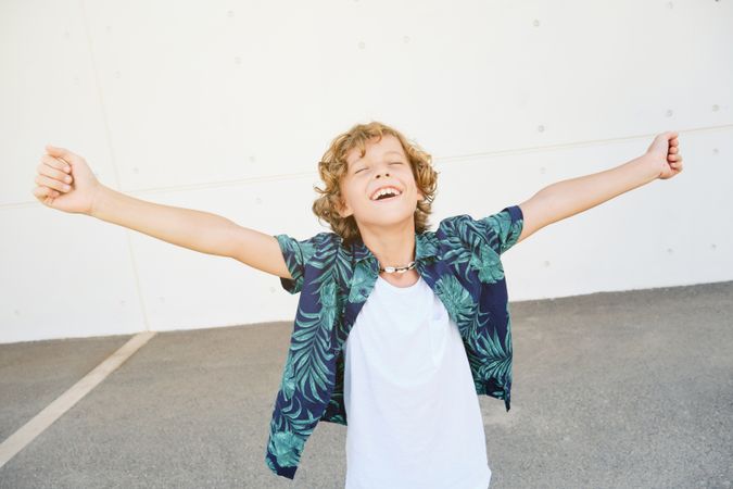 Cheerful boy with arms outstretched on pavement