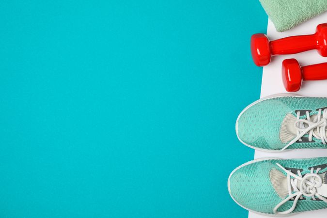 Flat lay composition with dumbbells, towel and sneakers on color background