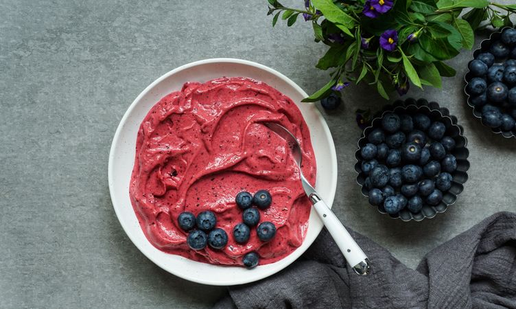 Smoothy of fresh bog blueberries and raspberries in bowl near napkin