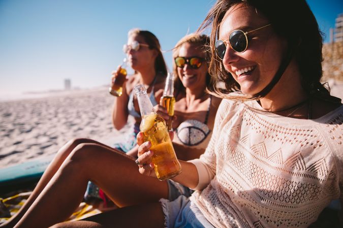 Group of young women drinking beer at the beach