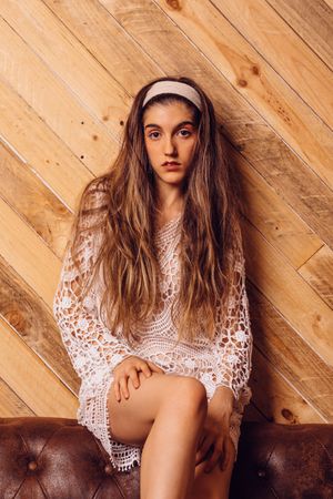 Young woman in white dress sitting on couch