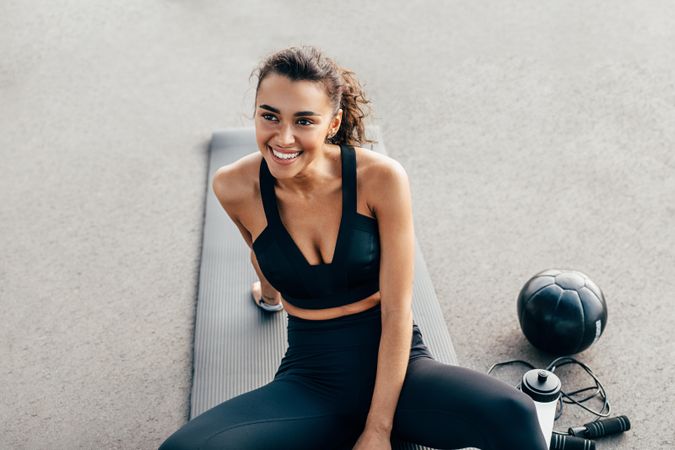 Happy woman on yoga mat with medicine ball