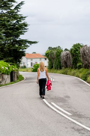 Joyful woman walking on marked road looking away