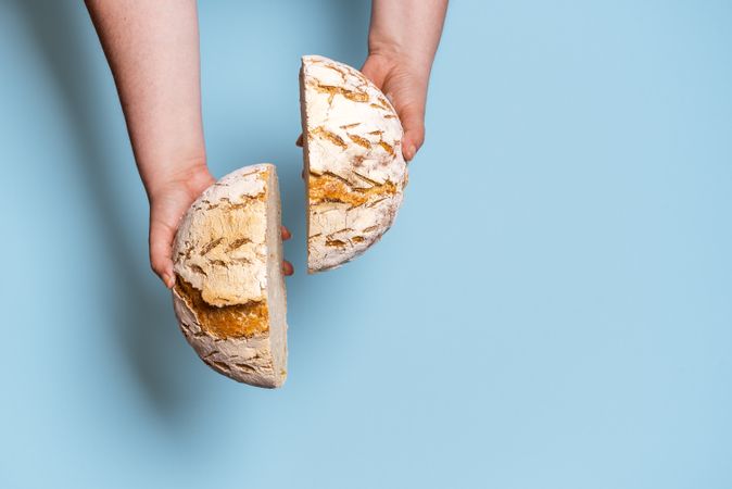 Bread sliced in two held in woman’s hands
