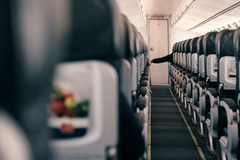 Unrecognizable hand reaching across a row in a plane
