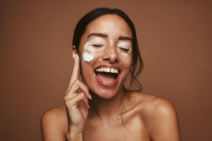 Happy young woman applying cream for vitiligo