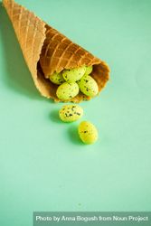 Waffle cone with small speckled eggs on green pastel background 432yaj