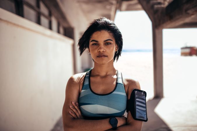 Female with mobile phone on armband taking a break after running workout