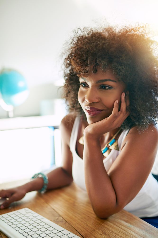 Vertical composition of woman sitting at her desk looking at computer monitor