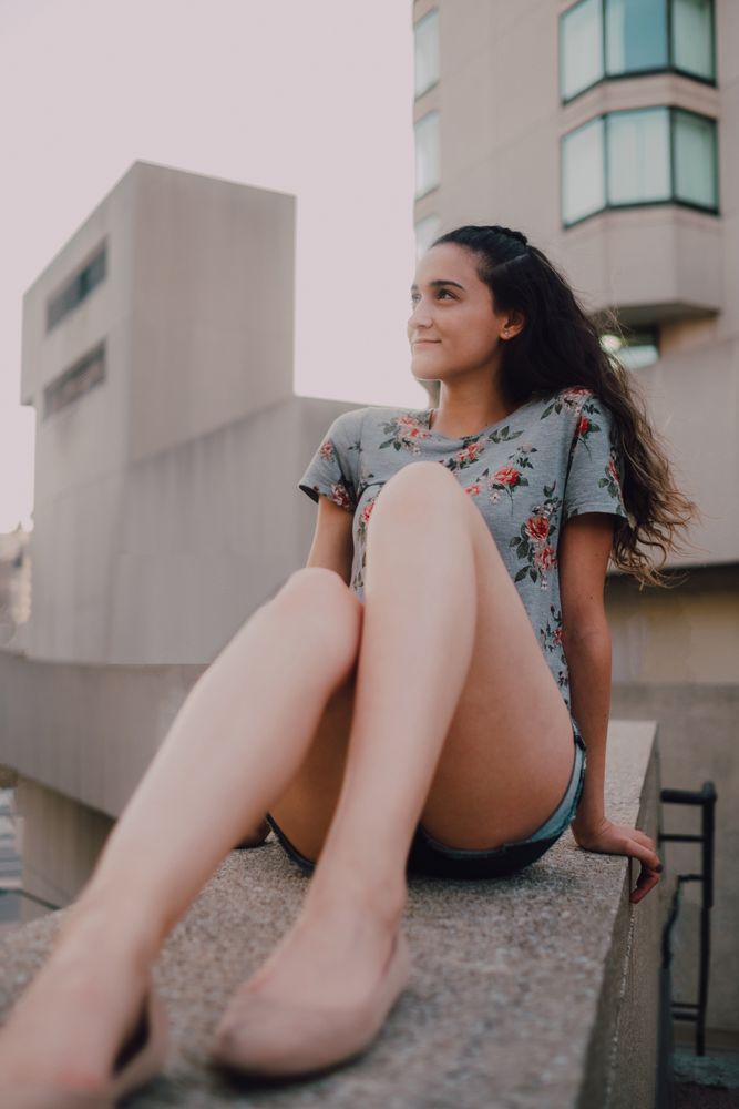 Smiling modern woman sitting on parapet