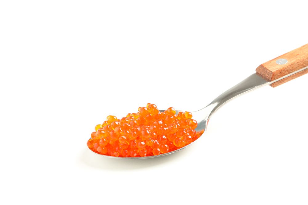 Spoon with red caviar isolated on blank background, closeup