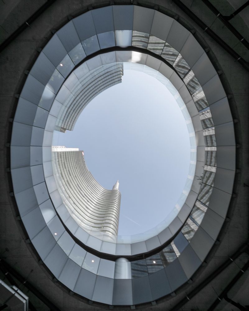 Ground view of round glass ceiling looking up to high rise buildings