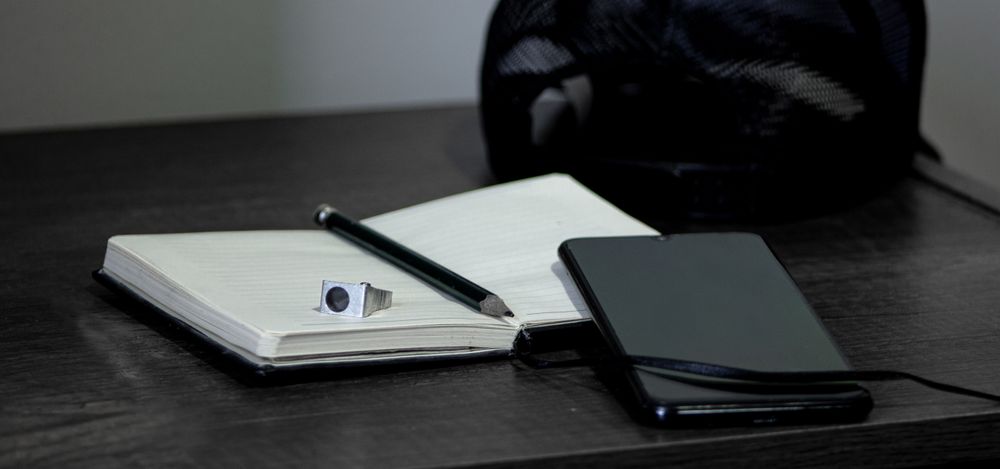 Grayscale photo two notebooks and a pen on desk