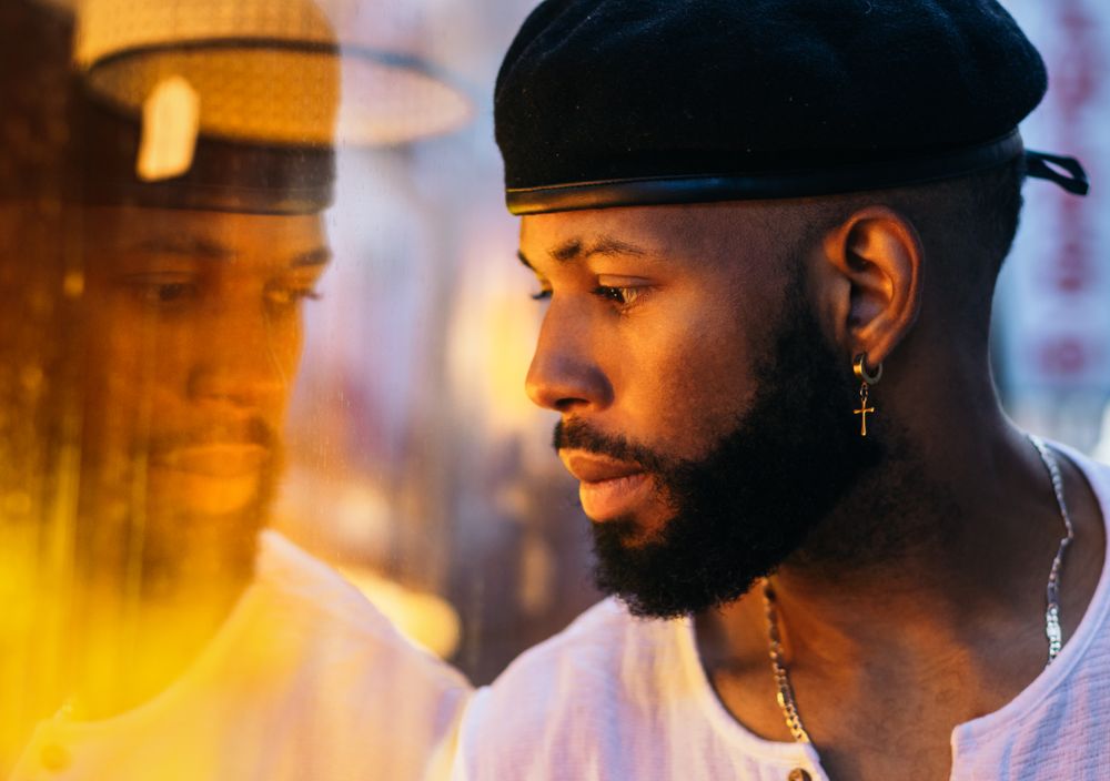 Black man near a glass. reflection and warm light
