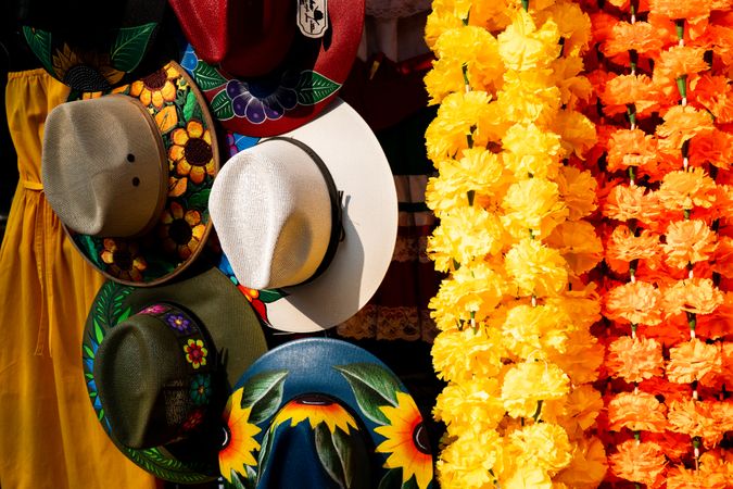 Hats and strings of flowers for sale at market