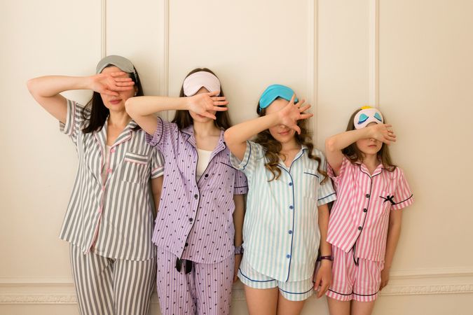 Group of girls in pajamas with hands over faces.