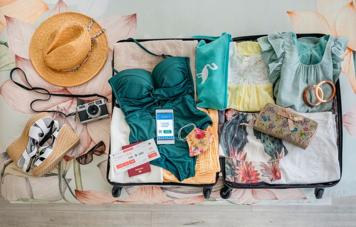 Open suitcase with woman luggage for beach vacation and digital health passport