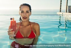 Attractive female enjoying cocktail at resort pool 0g6ajb