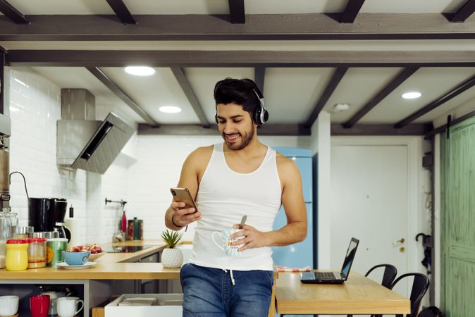 Young male with smartphone and cup of tea