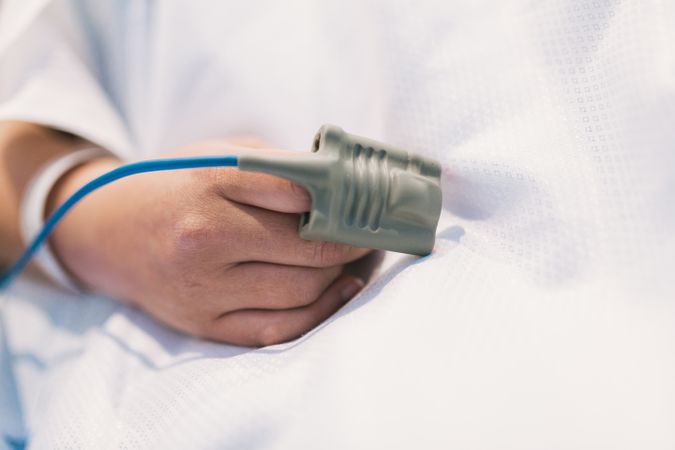 Crop patient with pulse oximeter in hospital