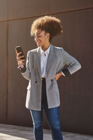 Smiling Black woman browsing smartphone in street