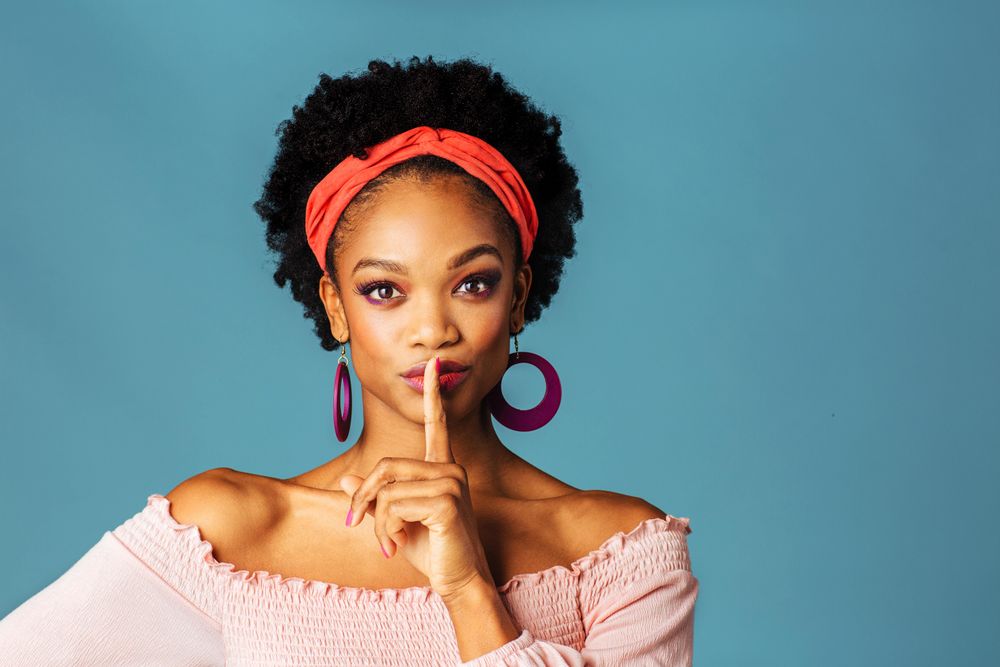 Studio shoot of curious Black woman with finger on her mouth