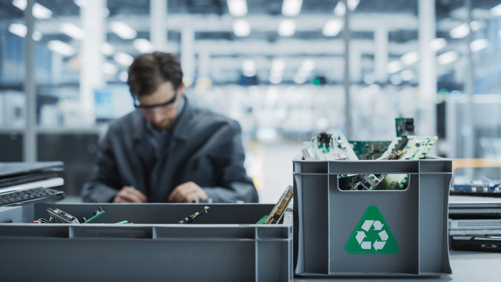 Male Worker Disassembling Old Laptops To Recycle Electronic Components For Sustainable Microchip Production At Electronics Factory.
