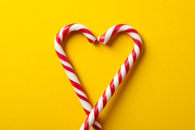 Sweet candy canes on yellow background, space for text