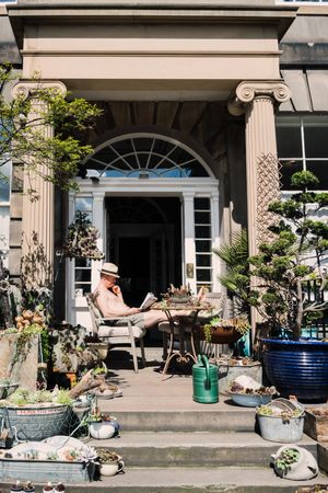 Man on porch with decorative plants in sunlight