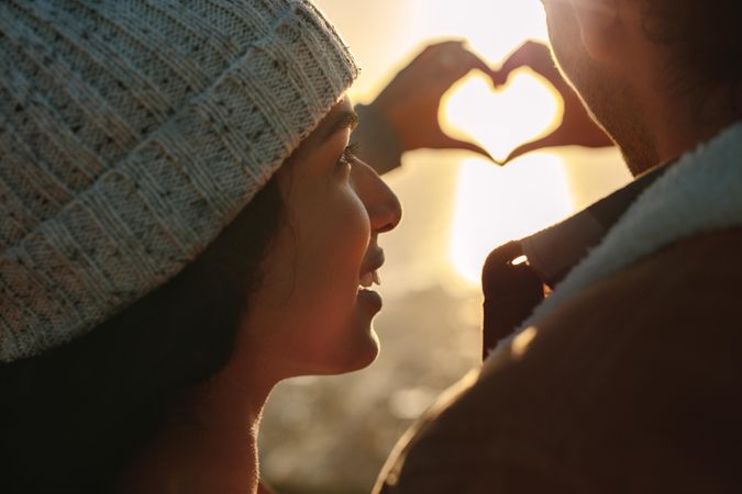 Close up of young man and woman in love gesturing a heart with fingers
