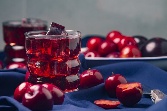 Red beverage near fresh fruits on cloth