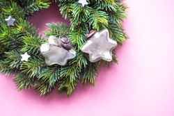 Close up of Christmas wreath with decorative stars on pink background