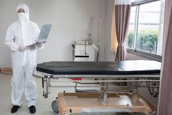 Portrait of doctor in PPE suit holding patient clipboard at emergency room