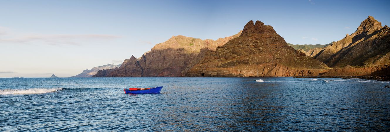 Blue sailboat in sea and beautiful rocks