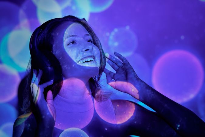 Merry female in headphones looking up