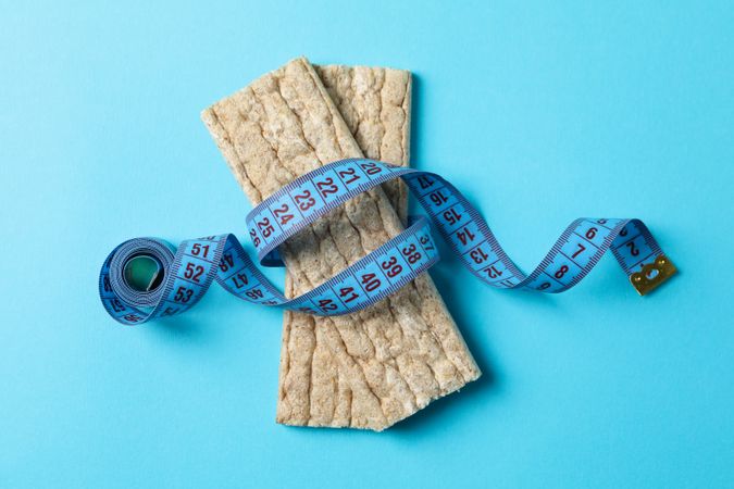Measure tape and diet bread on blue background